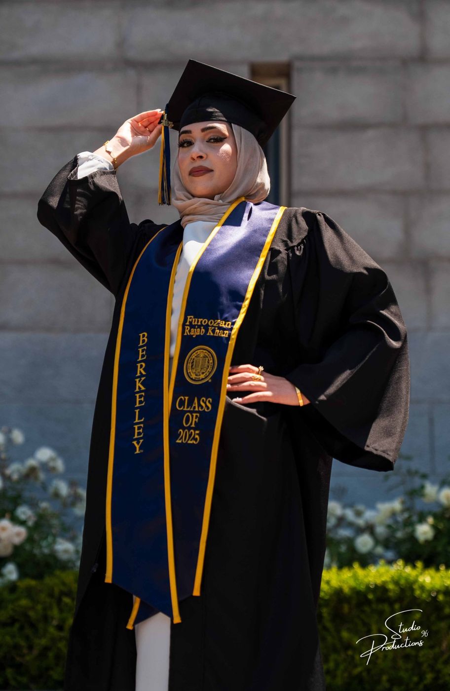 Confident graduate portrait in cap and gown on campus