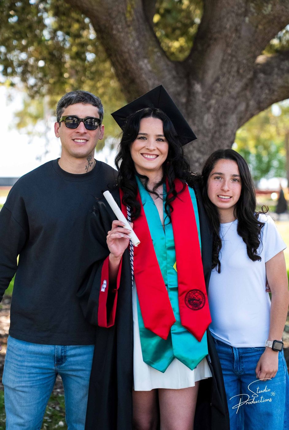 Graduate posing with two family members, holding her diploma