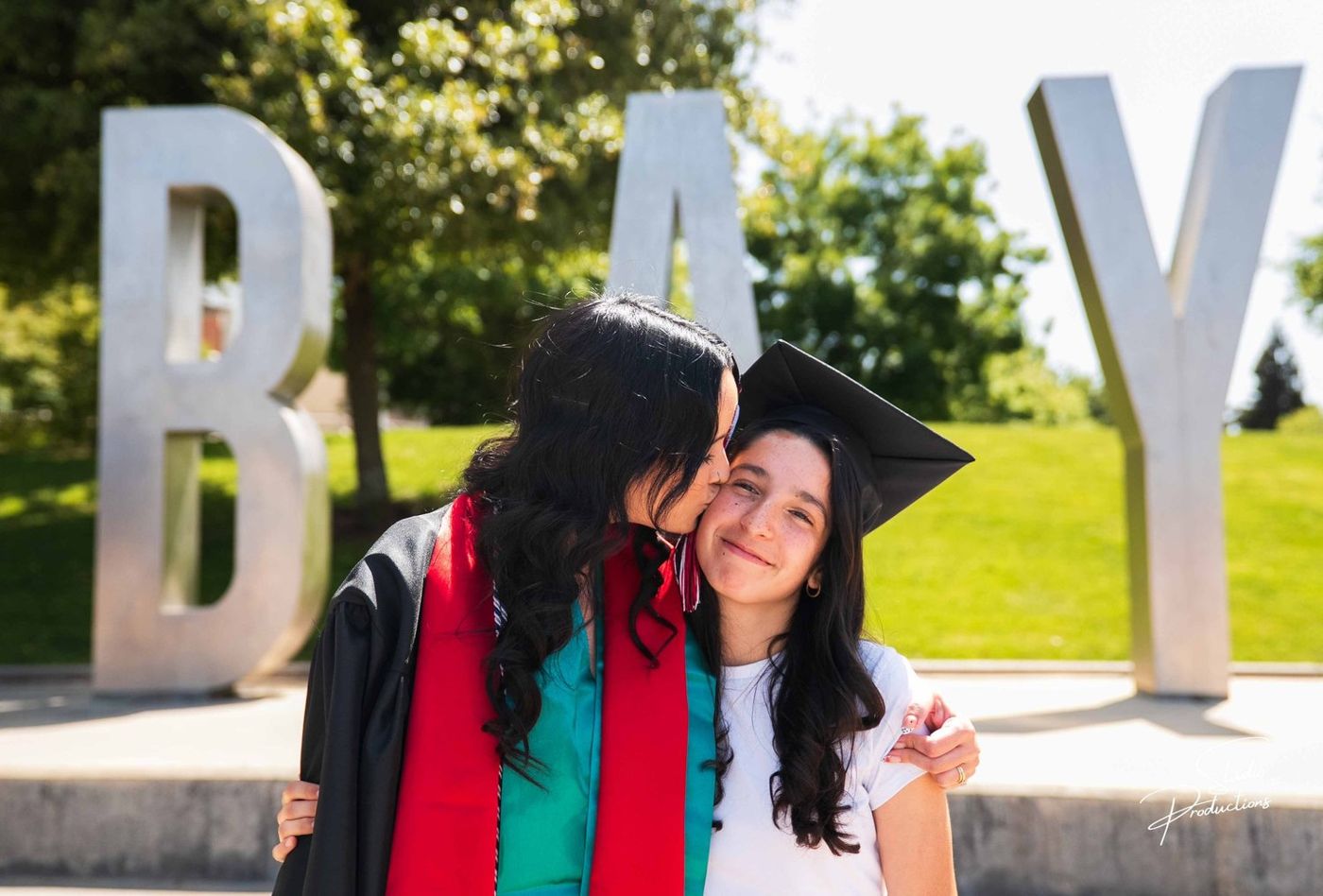 Graduate and a companion posing playfully by large sculptural letters