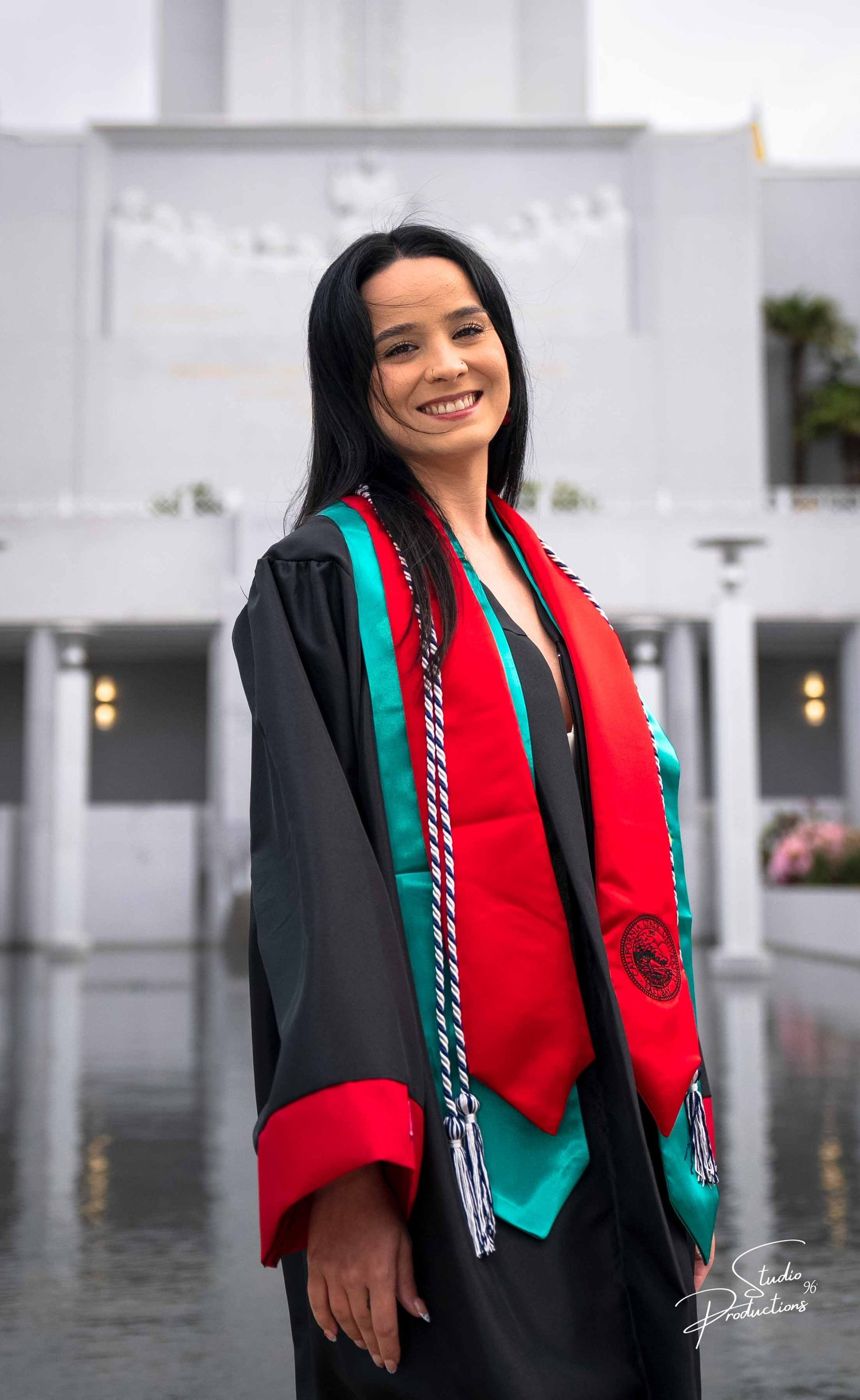 Close-up smiling portrait of the graduate in cap, gown, and sash