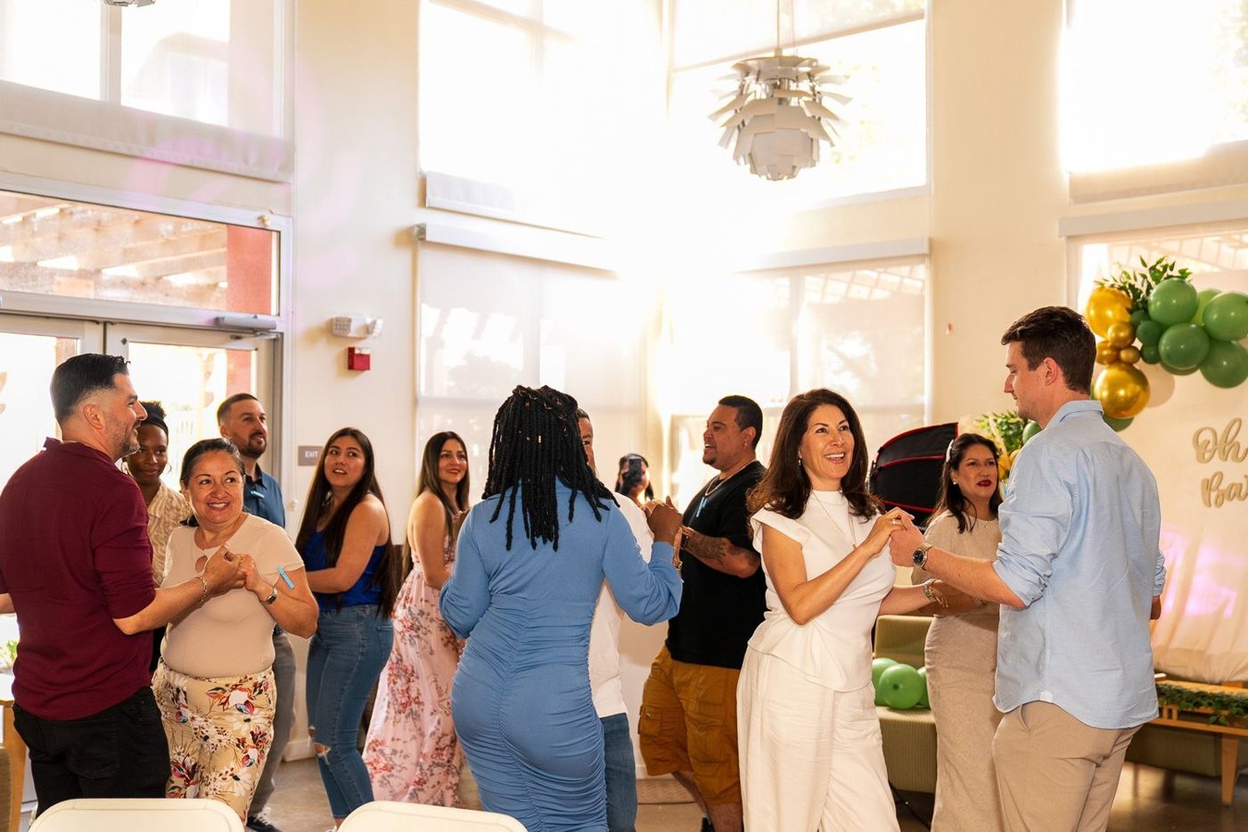 Wide shot of guests mingling in the venue near the "Oh Baby" balloon backdrop