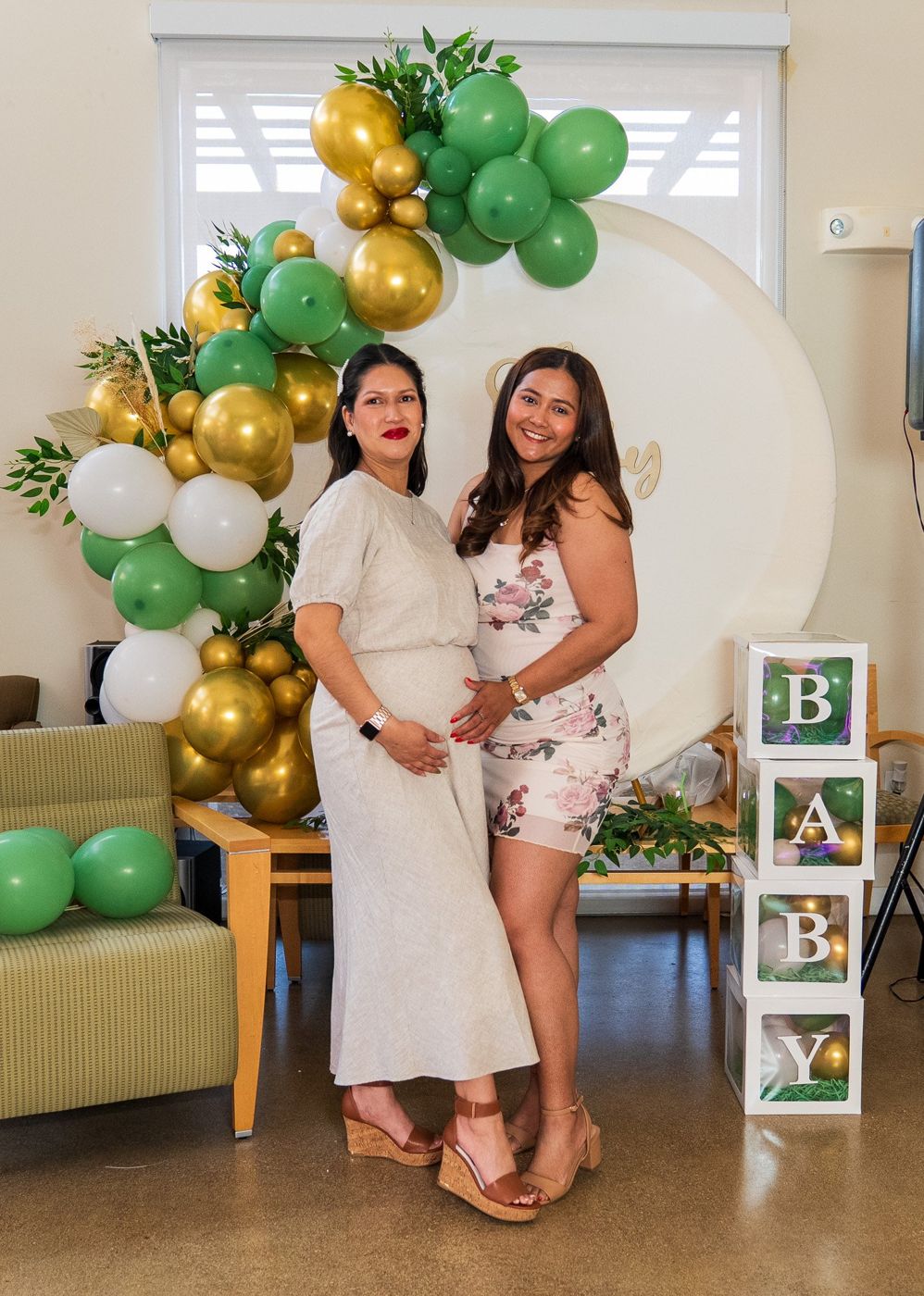Mom-to-be posing with a guest beside the "Oh Baby" balloon arch and stacked baby blocks
