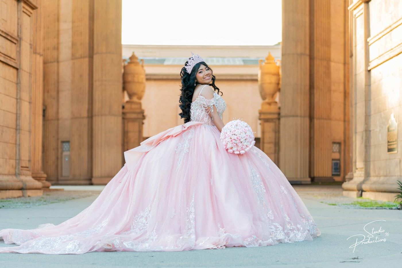 Quinceañera in a pink gown between the columns of the Palace of Fine Arts