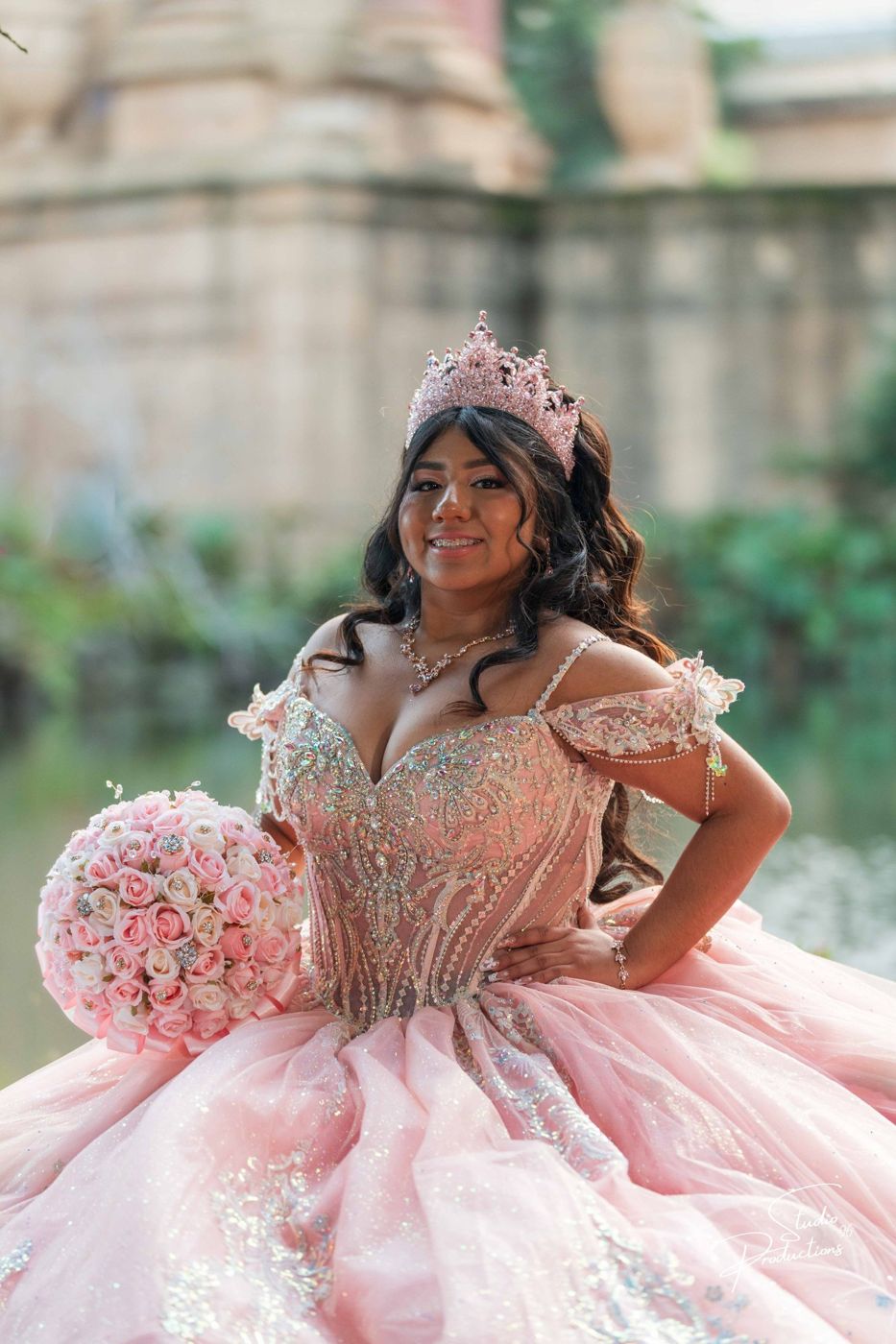 Quinceañera posing with a hand on her hip by the lagoon
