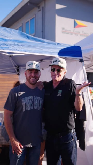Two men in The Nut caps at a street-fair booth