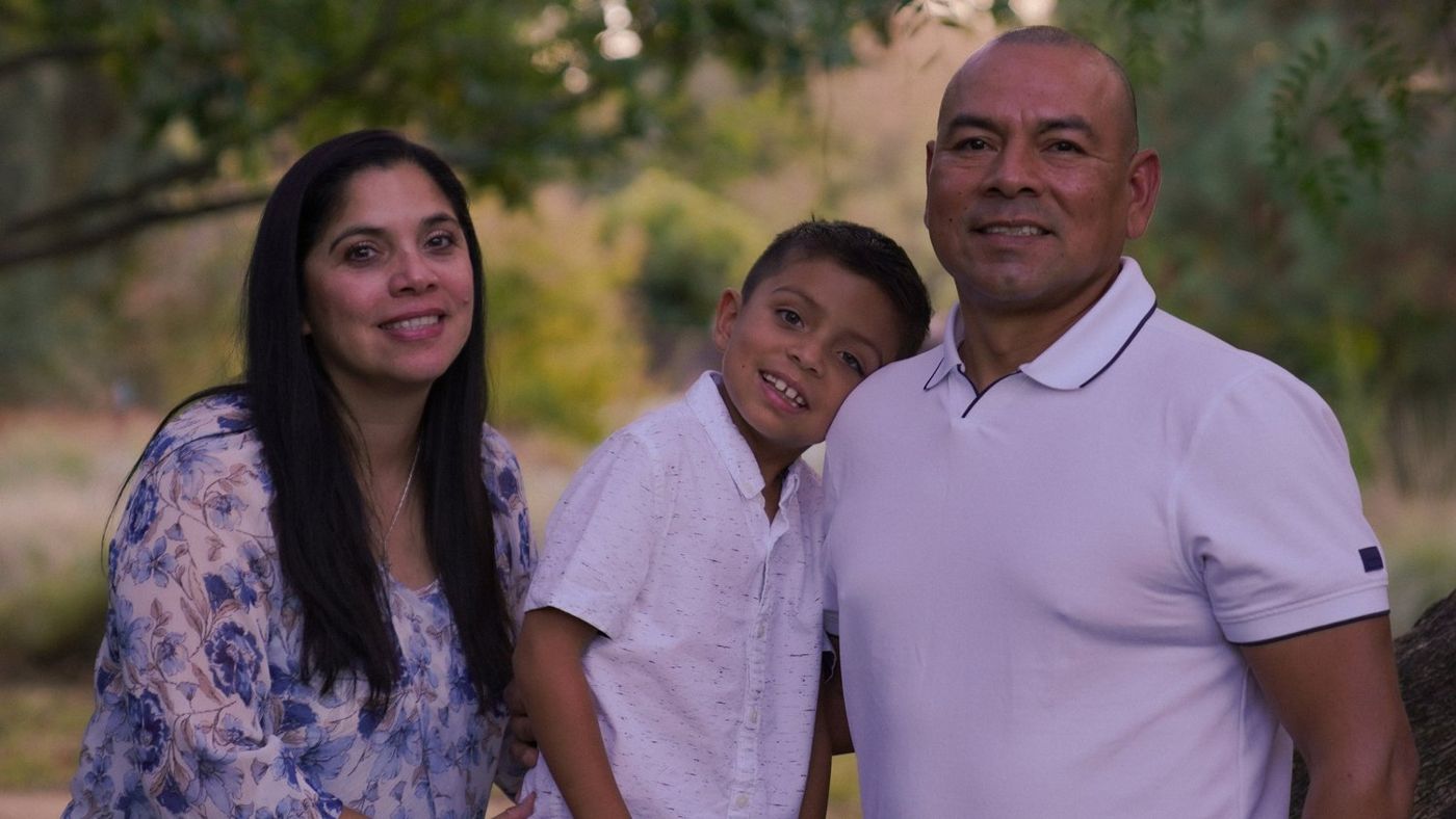 Family of three posing together outdoors