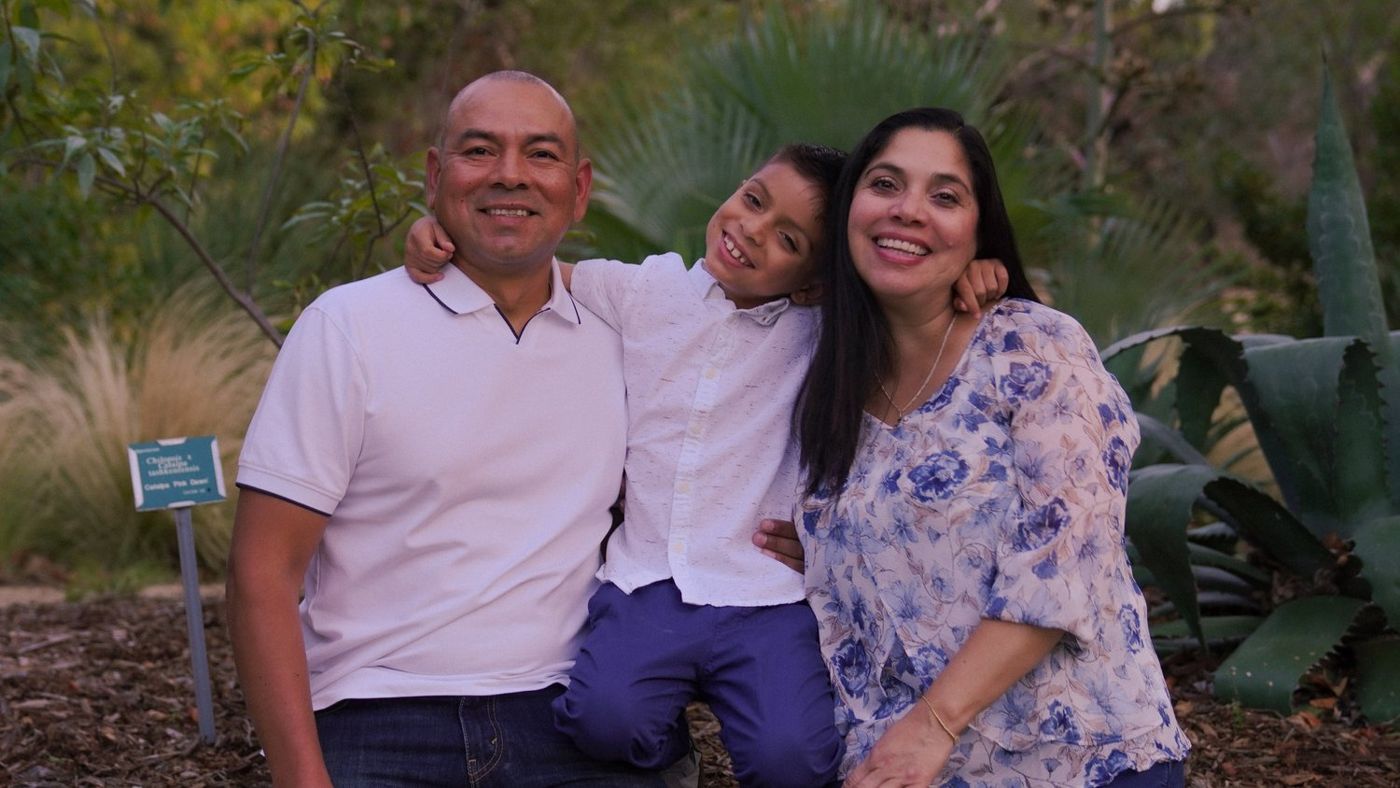 Posed family portrait, father holding his son, all three smiling