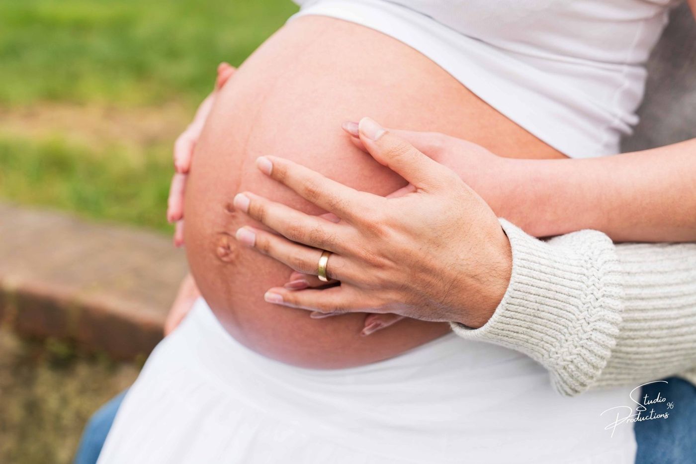 Close-up of the couple's hands cradling the baby bump