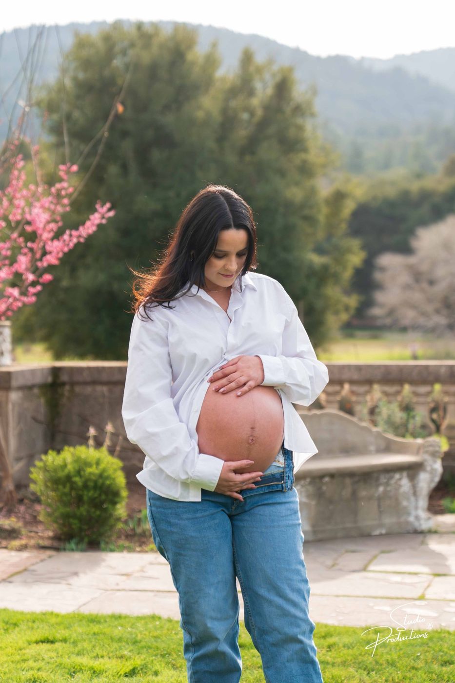 Solo portrait of the expecting mother standing by a stone wall at the estate