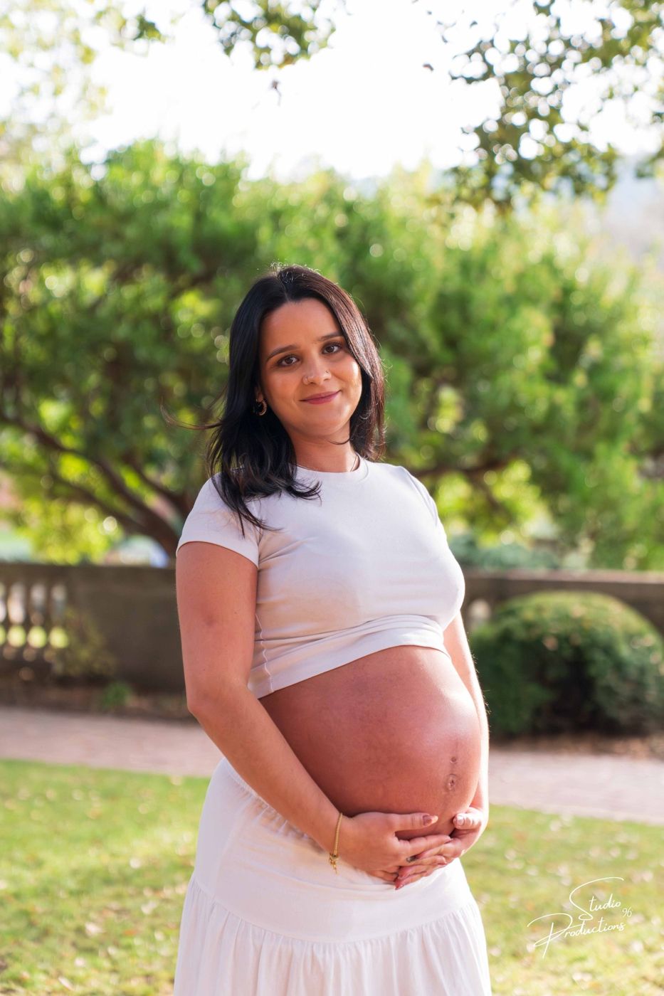 Solo portrait of the expecting mother smiling in the garden light