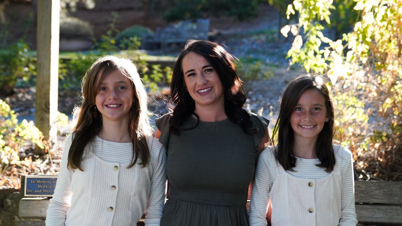Mother and her two daughters posing together near the garden entrance