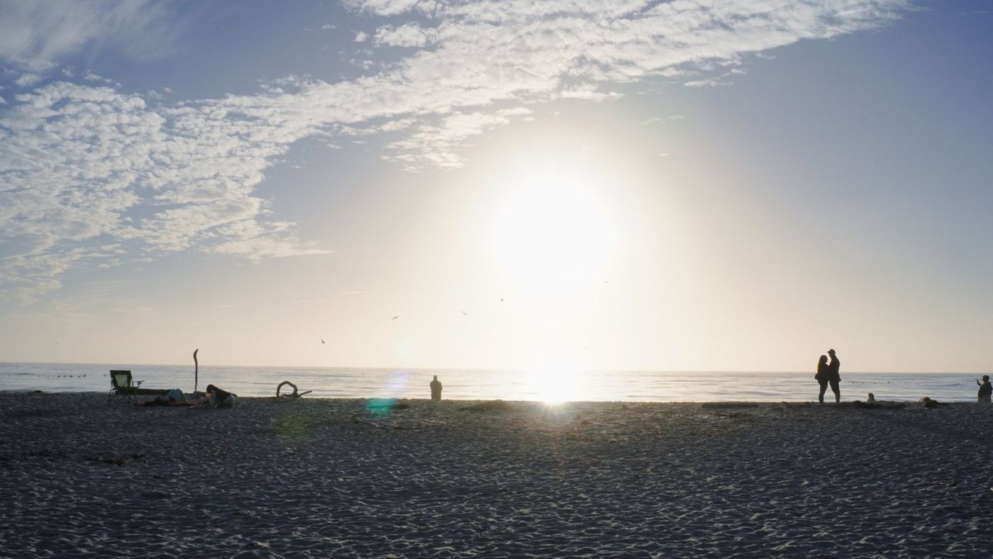 Wide beach view with the bright evening sun low over the water