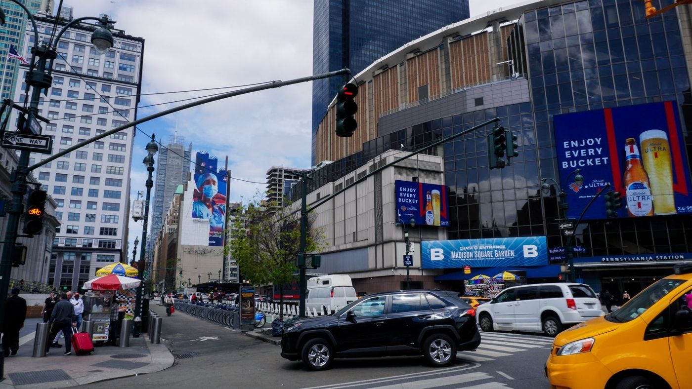 A busy Manhattan intersection with a yellow taxi and billboards