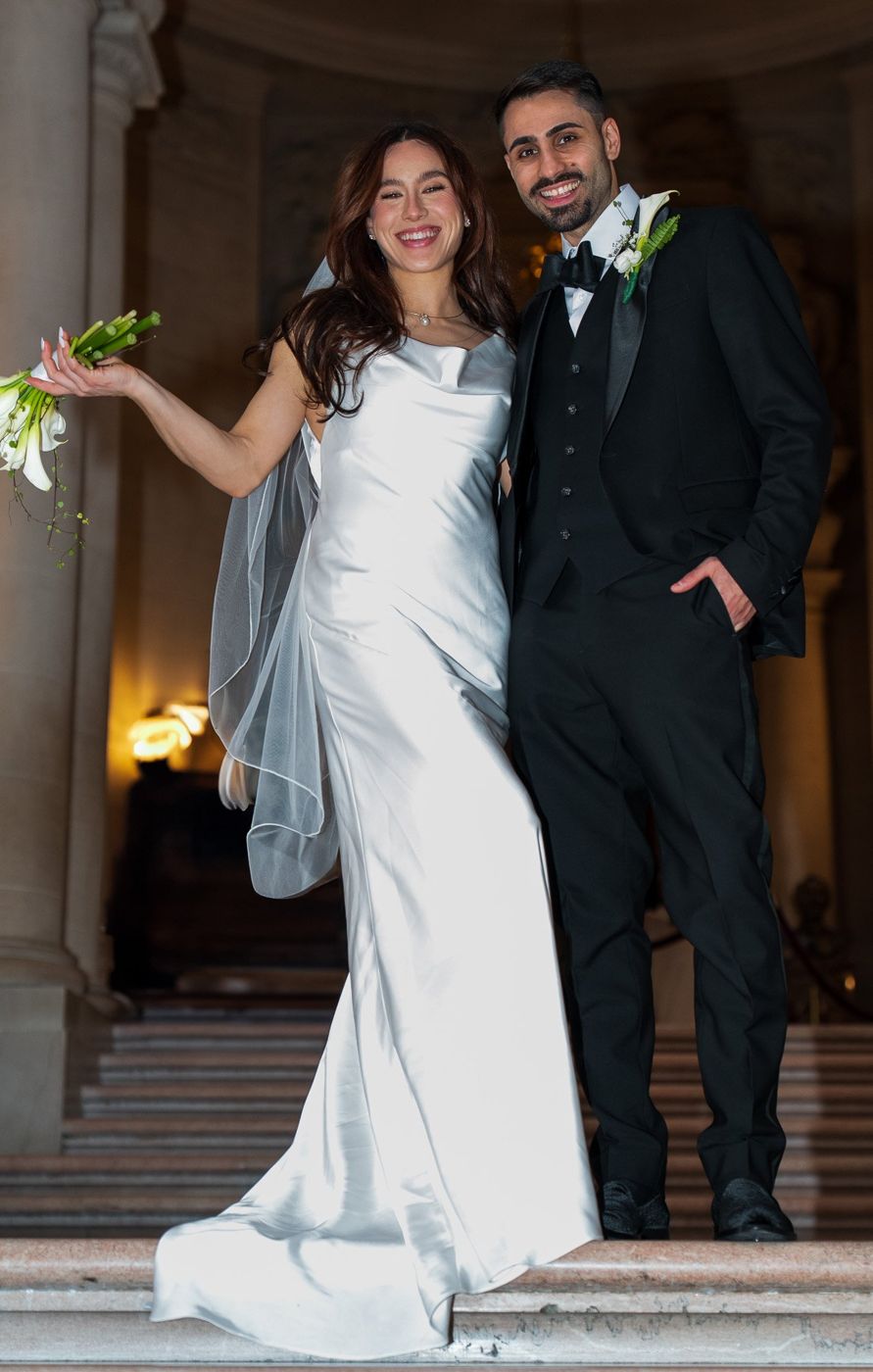 Bride descending the staircase, veil trailing, groom looking on