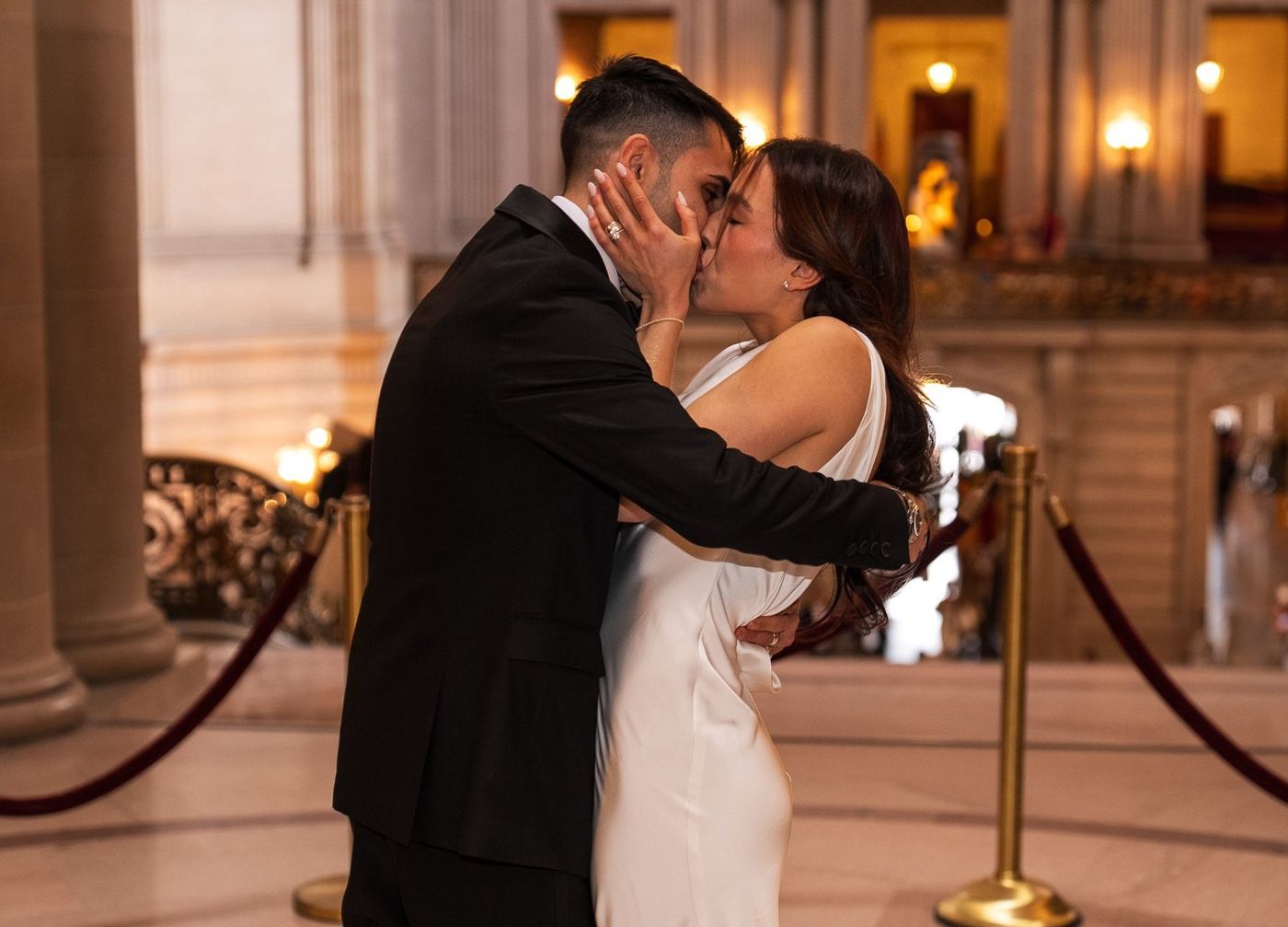 The couple sharing their first kiss during the ceremony as the officiant looks on