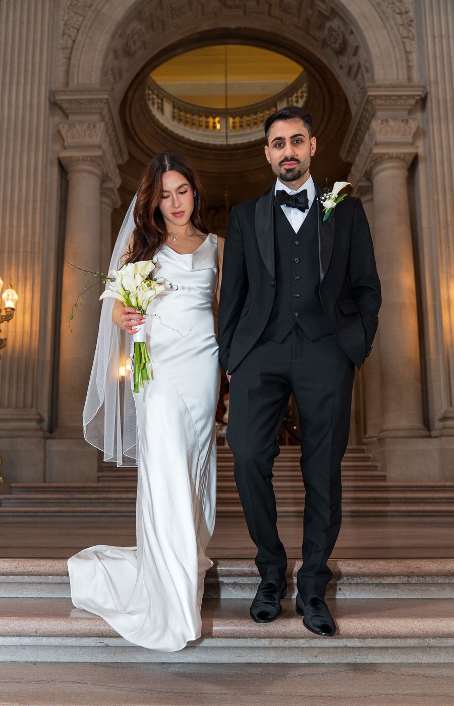 Full-length portrait of the bride and groom on the rotunda staircase