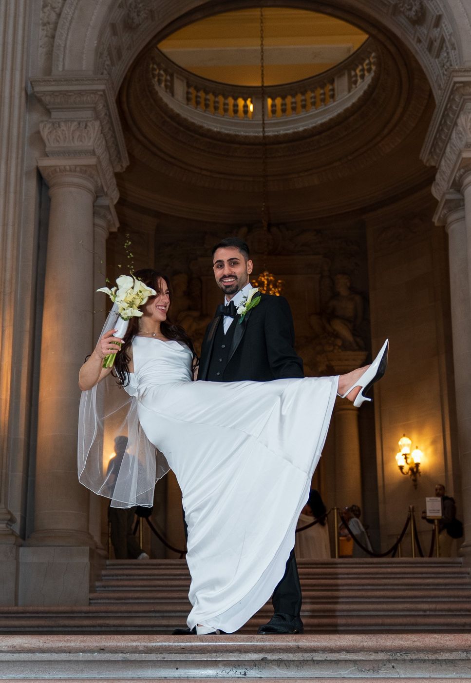 The groom lifting the bride's veil in a playful spin at the top of the stairs