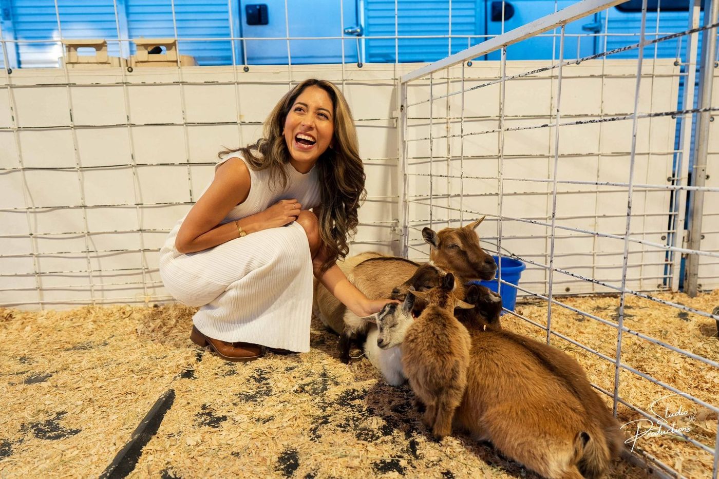 The bride-to-be laughing inside a small pen with two goats