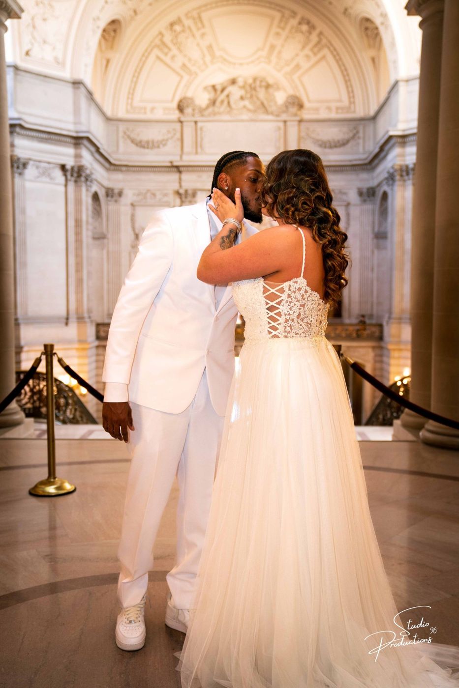 Bride and groom sharing an emotional embrace, both in white