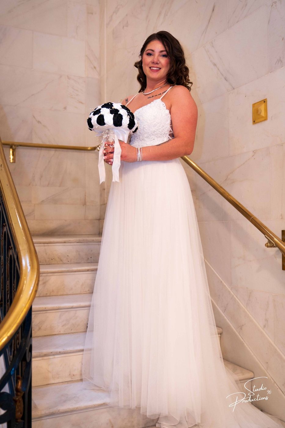 Full-length solo portrait of the bride on the staircase, holding her bouquet
