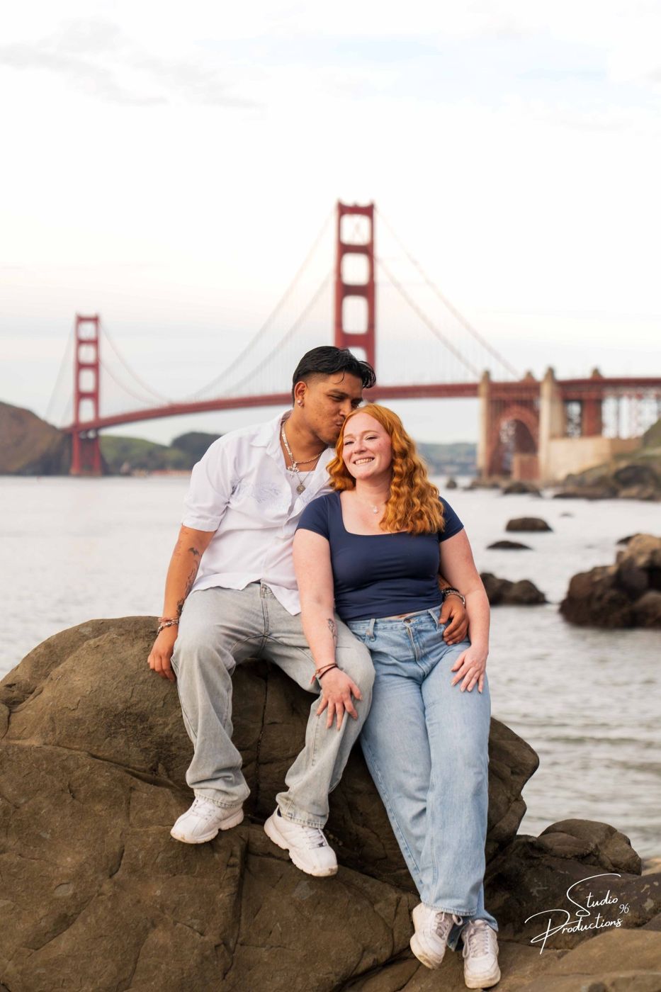 Couple sitting on coastal rocks with the Golden Gate Bridge in the background