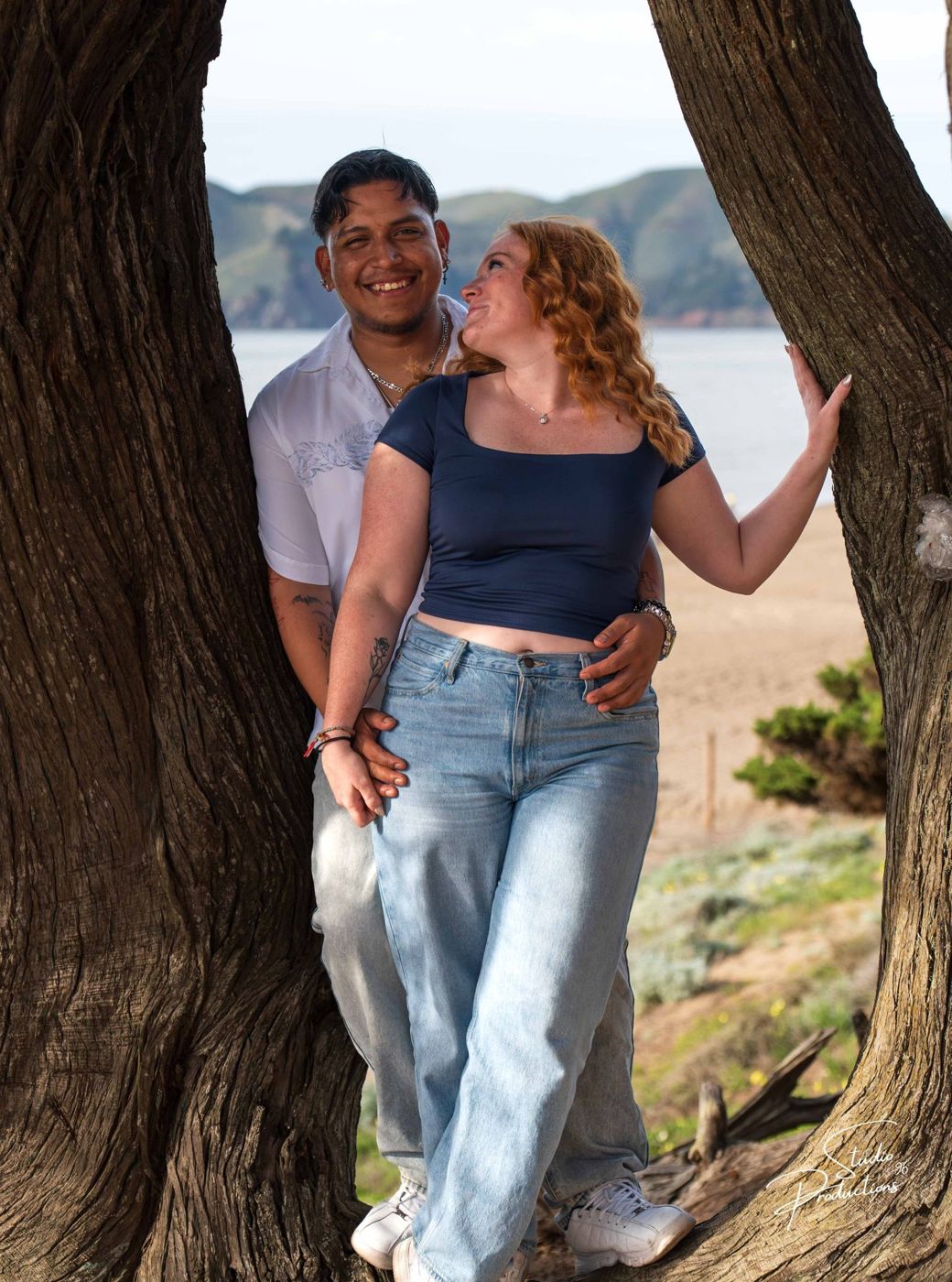 Playful embrace framed by tree branches on the bluff